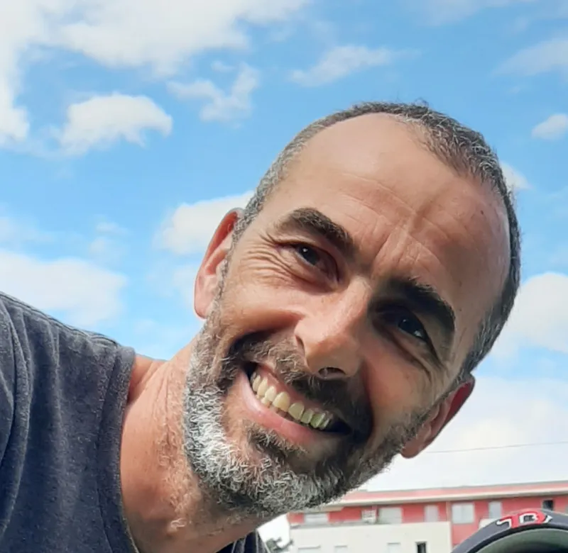 Portrait de Thomas, souriant devant un ciel bleu